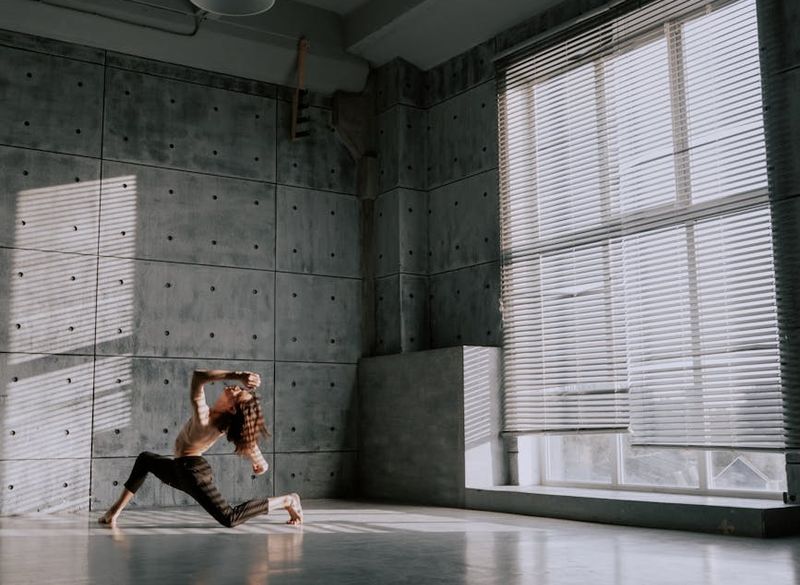 Woman holding a challenging balance pose in a spacious, minimalist room.